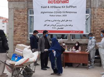 A Woman Participant is helped with a her Food Kit Delivery.  